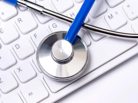 Blue stethoscope on computer keyboard on white table background. Online medic Stock Photos