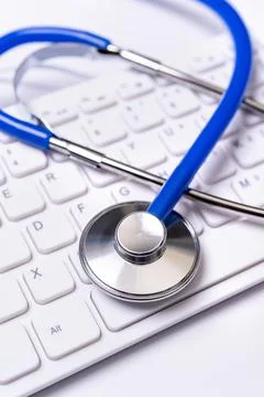 Blue stethoscope on computer keyboard on white table background. Online medic Foto stock