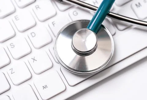 Blue stethoscope on computer keyboard on white table background. Online medic Stock Photos
