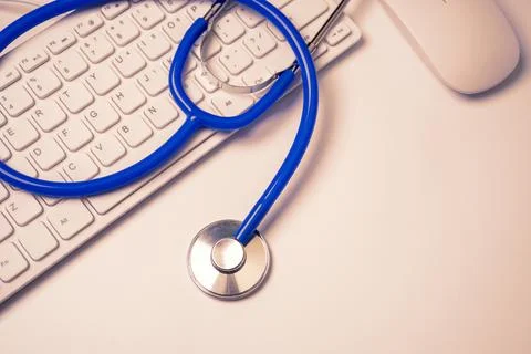Blue stethoscope on computer keyboard on white table background. Online med.. Stock Photos