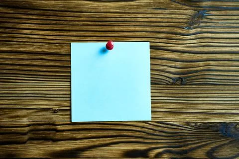 Blue sticker fixed with a red button on a wooden wall. Foto stock