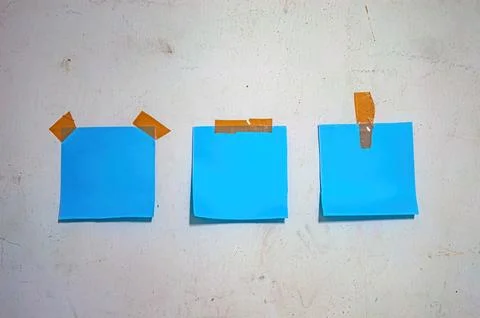 Blue sticky notes taped to a worn white wall, perfect for concepts of plann.. Stock-Fotos