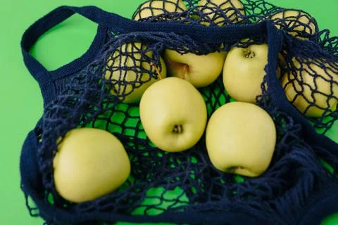 Blue string bag with green apples on a green background Foto stock