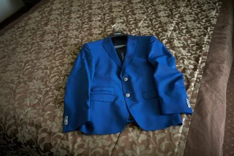Blue suit jacket elegantly displayed on patterned bed, showcasing sophistic.. Stock Photos