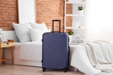Blue suitcase with an extended handle standing on the floor in a modern hotel Photos