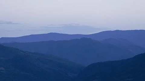 Blue sunset with the setting sun behind the mountains Stock Photos