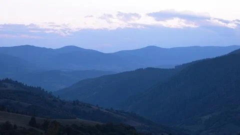 Blue sunset with the setting sun behind the mountains Stock Photos