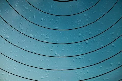 Blue surface dotted with raindrops, displaying graceful curved lines. A close-up Stock Photos