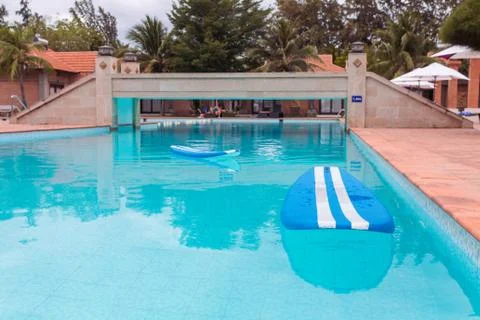 Blue surfboard floating on blue pool surface Stock Photos