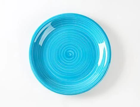 Blue swirl ceramic plate on plain surface Stock Photos