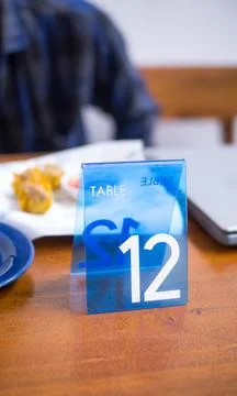Blue Table Number 12 Tag on Wooden Restaurant Table Stock Photos