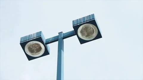 Blue tall light post with two turned off circle pot light in squares opposite Stock Footage 250277253