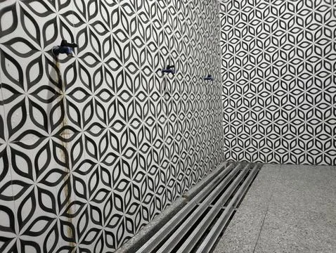 Blue tap stands beside patterned tile wall Stockfoto's