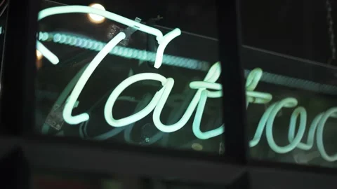Blue Tattoo Light Sign on a Window From a Barbershop and Tattoo Studio Stock Footage 140618653