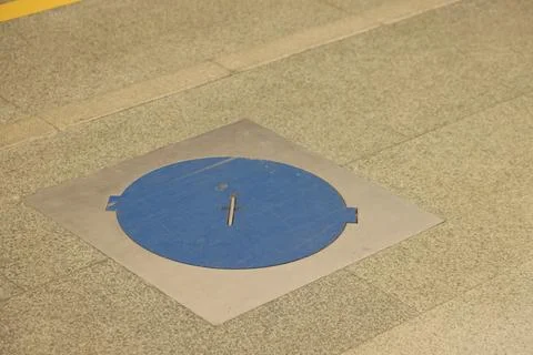 Blue technological hatch on the floor of the metro station, close-up photo. Stock Photos