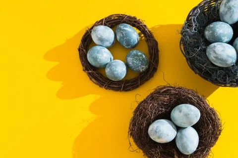 Blue textured colored Easter eggs in a nest or wreath on a bright yellow holi Stock Photos