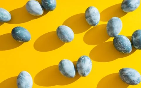 Blue textured colored Easter eggs on a bright yellow holiday background backd Stock Photos