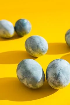 Blue textured colored Easter eggs on a bright yellow holiday background backd Stock Photos