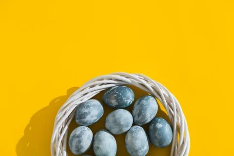 Blue textured colored Easter eggs in a nest or wreath on a bright yellow holi Stock Photos