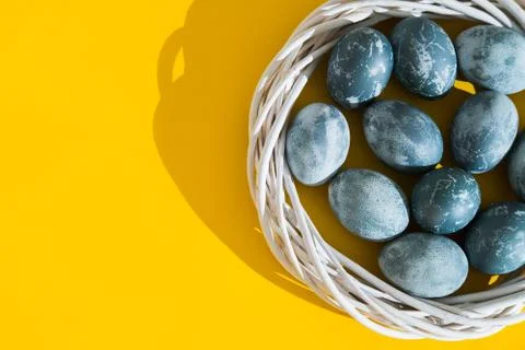 Blue textured colored Easter eggs in a nest or wreath on a bright yellow holi Stock Photos