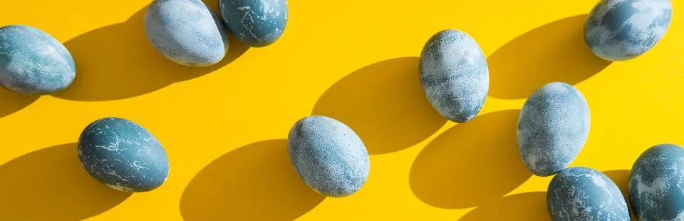 Blue textured colored Easter eggs on a bright yellow holiday background backdrop Stock Photos