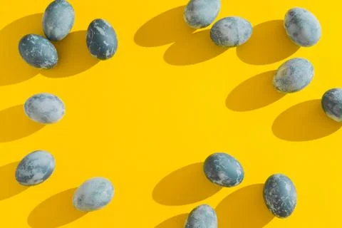 Blue textured colored Easter eggs on a bright yellow holiday background backdrop Stock Photos