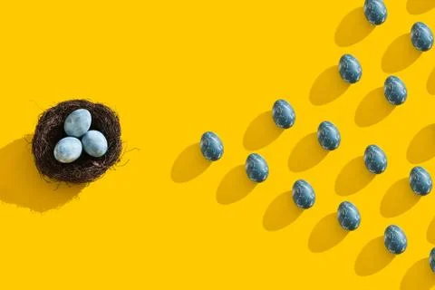 Blue textured colored Easter eggs and bird nest on a bright yellow holiday Stock Photos