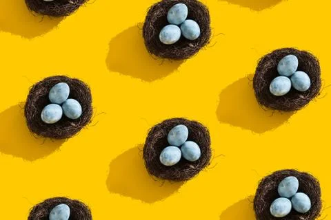 Blue textured colored Easter eggs and bird nest on a bright yellow holiday Stock Photos