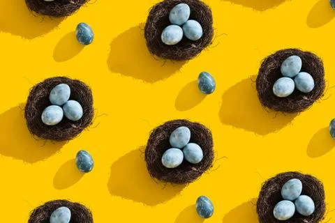 Blue textured colored Easter eggs and bird nest on a bright yellow holiday Stock Photos