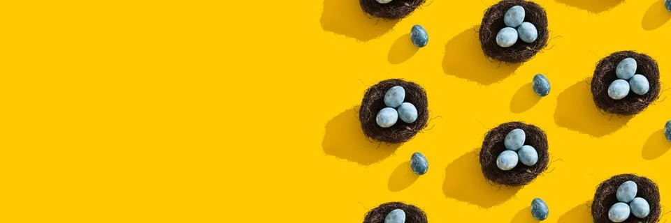 Blue textured colored Easter eggs and bird nest on a bright yellow holiday Stock Photos