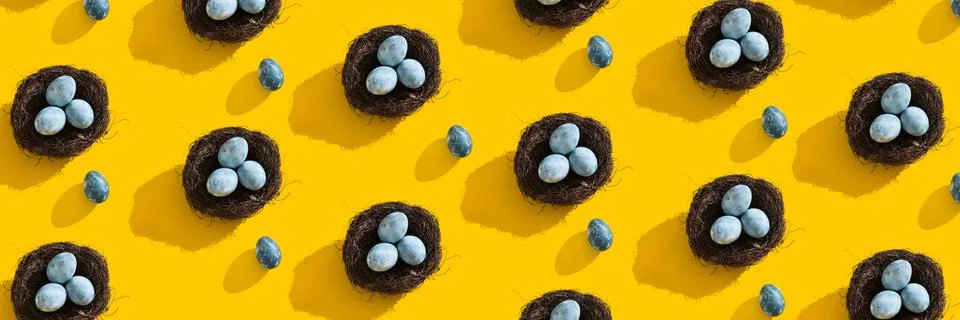 Blue textured colored Easter eggs and bird nest on a bright yellow holiday Stock Photos