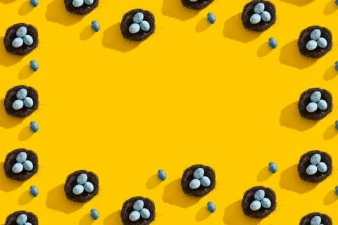 Blue textured colored Easter eggs and bird nest on a bright yellow holiday Stock Photos