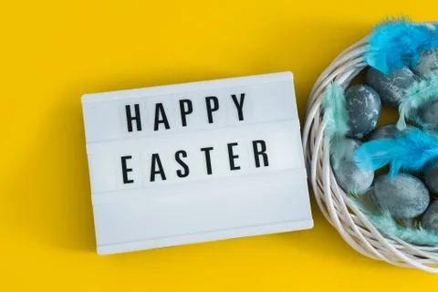 Blue textured painted Easter eggs, feathers and a luminous decorative board Stock Photos