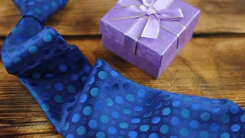 Blue tie with a small forged gift on a wooden background Video stock 152609700