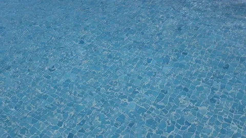 Blue tiled pool water with gentle ripples and reflections on a sunny day Stock Footage 319908047