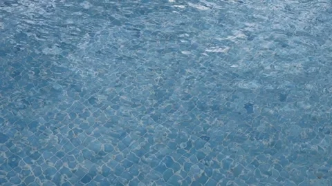 Blue tiled pool water with gentle ripples and reflections on a sunny day Stock Footage 319908048