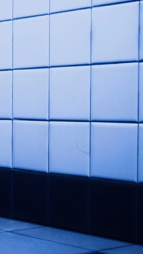 Blue tiled wall with light and shadow in a restroom setting during the day Stock Footage 334724946