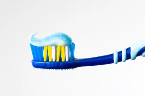 Blue toothbrush with blue toothpaste on a light background. Stock Photos
