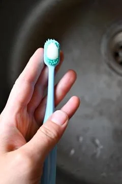 A blue toothbrush in the hand with white toothpaste Stock Photos