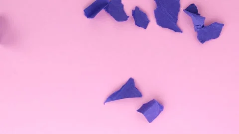 Blue torn papers fall on the pink surface of the table Stock Footage 310030721