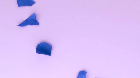 Blue torn papers fall on the pink surface of the table. Stock Footage 310030722