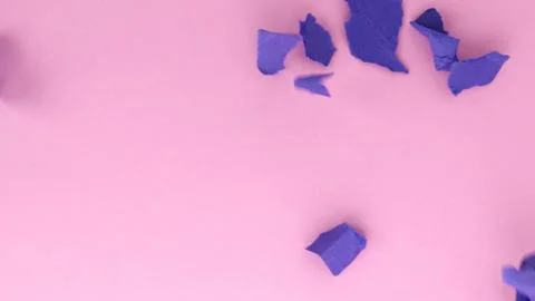 Blue torn papers fall on the pink surface of the table Stock Photos
