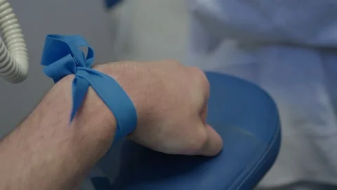 Blue Tourniquet on Patient Arm While Nurse Presses Cotton Swab After Blood Draw Stock Footage 343985996