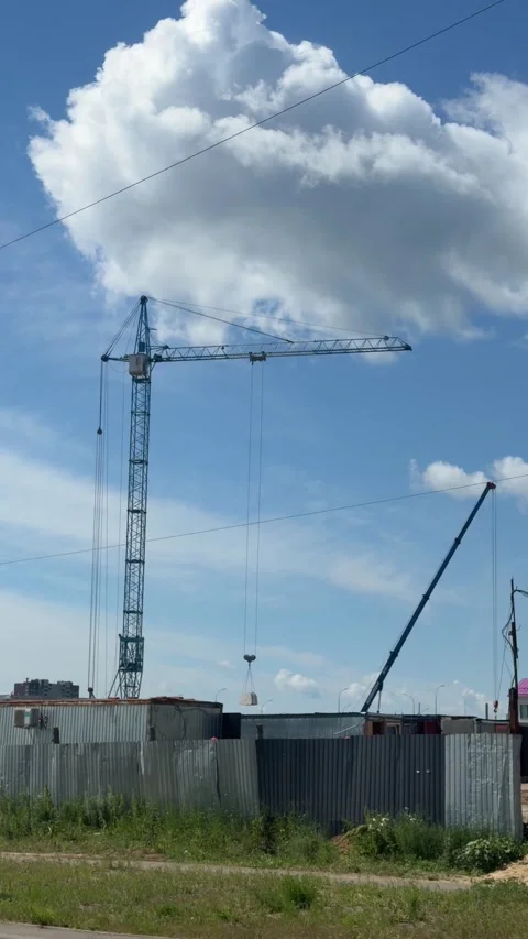 A blue tower crane lifting a concrete block at a construction site Stock Footage 337627835