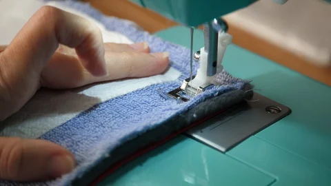 Blue towling is fed through a sewing machine Stock Footage 129519485