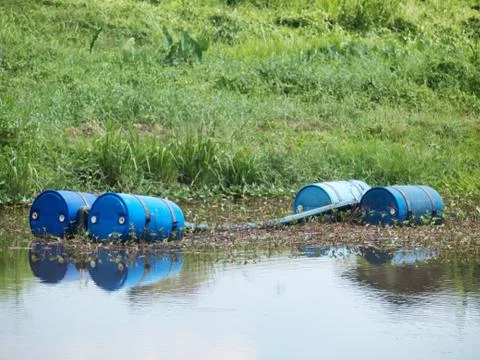 Blue toxic drums in river Fotos Stock