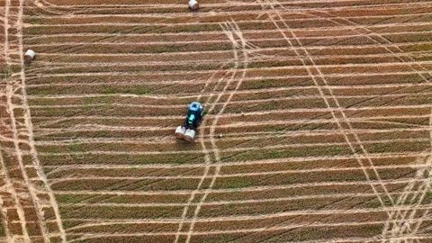 Blue tractor baling hay on patterned farmland with visible tire tracks Stock Footage 321335678