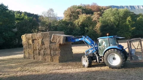 Blue tractor catching a bale of straw Stock Footage 139413761