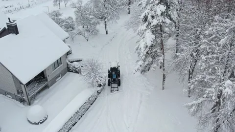 Blue tractor cleans up snow from the yard Stock Footage 233469997
