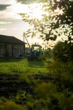 Blue tractor in the evening, at sunset after a hard day's work.A green field Stock Photos